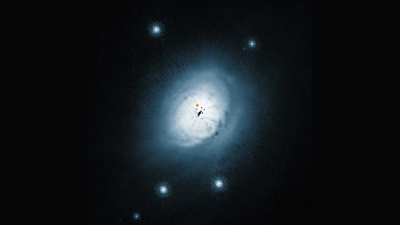 Диск навколо HD 100546, знятий телескопом «Габбл». Помаранчевою точкою позначена протопланета, чорні плями у центрі є ефектами, що з’явилися внаслідок обробки зображення. ESO, NASA, ESA, Ardila et al. / Wikimedia Commons
