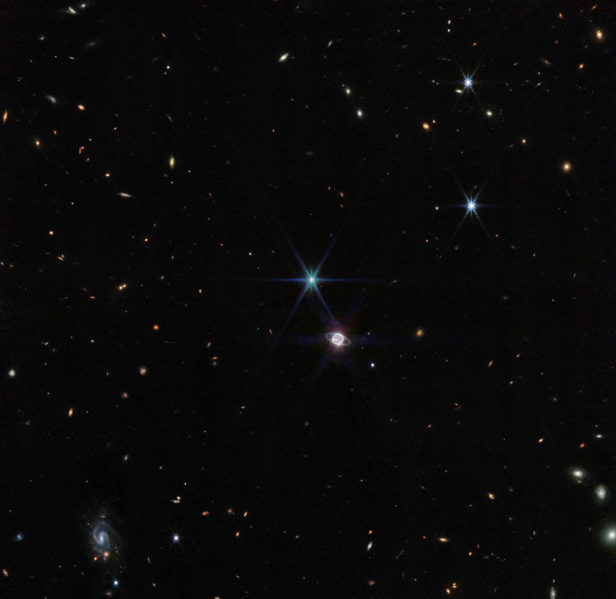 Спіральна галактика у нижньому лівому куті зображення може бути на відстані близько мільярда світлових років від нас. NASA, ESA, CSA, STScI, Joseph DePasquale (STScI)
