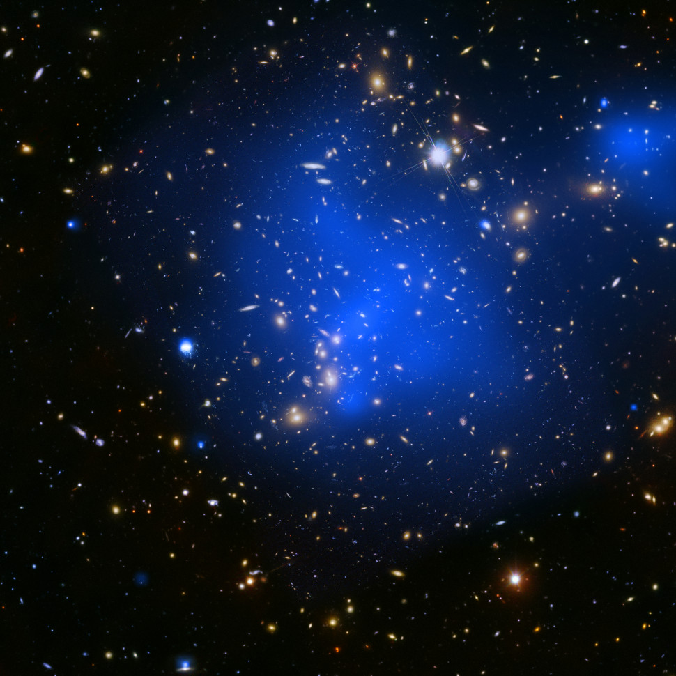 Abell 2744 також відоме як скупчення Пандори. Скупчення галактик — це найбільші гравітаційно пов’язані структури у Всесвіті. Це зображення поєднує в собі рентгенівські промені, зафіксовані «Чандрою» (дифузне випромінювання синього кольору) та дані оптичного світла від «Габбла» (червоний, зелений та синій кольори).