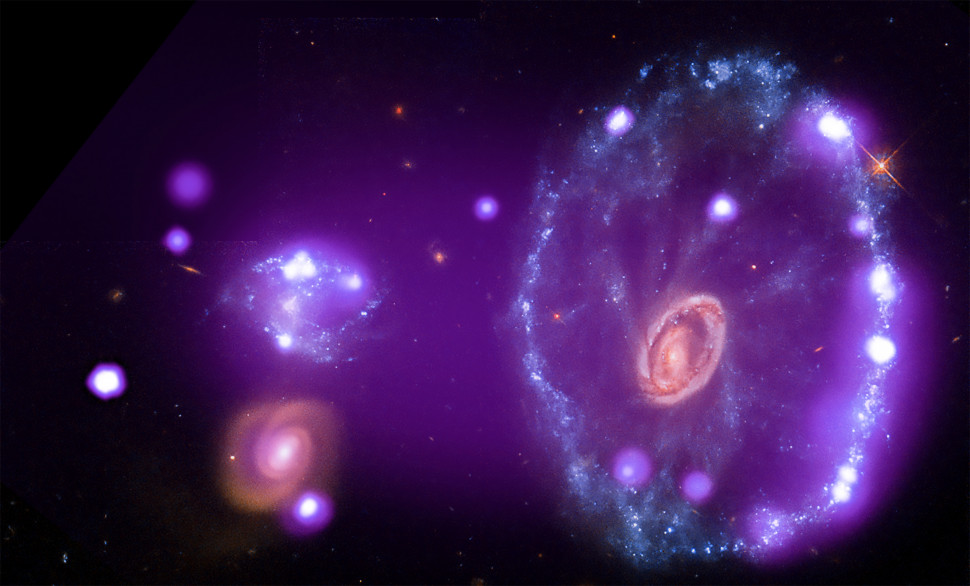 Ця галактика отримала незвичайну форму, коли інша, карликова галактика, зіштовхнулася із нею та пройшла крізь її диск. Зіткнення спричинило ударні хвилі, які прокотились через галактику та запустили процеси зореутворення. Рентгенівські промені «Чандри» (фіолетовий) показують збурений гарячий газ, який колись розміщувався у галактиці Колесо Воза, а тепер викинувся на відстань 150 000 світлових років від неї. Оптичні дані «Габбла» (червоний, зелений та синій) показують, де саме це зіткнення могло спричинити формування зірок.
